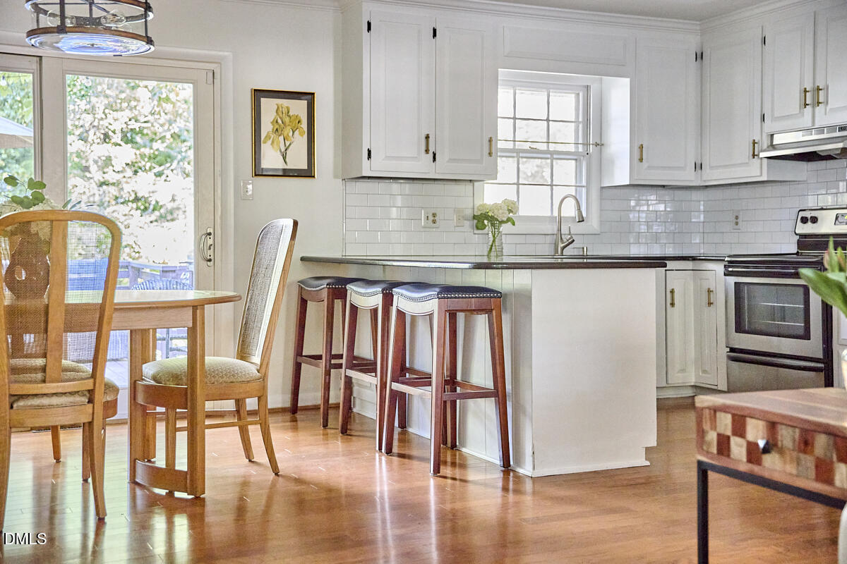 4916 Latimer Road Raleigh, NC 27609 - Photo 12 of 30 a kitchen with stainless steel appliances granite countertop a stove top oven a sink and white cabinets with wooden floor