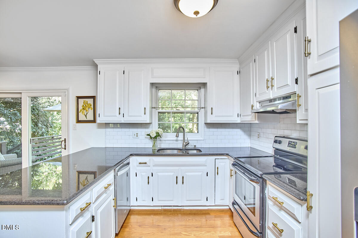 4916 Latimer Road Raleigh, NC 27609 - Photo 15 of 30 a kitchen with stainless steel appliances white cabinets a sink a stove a window and cabinets