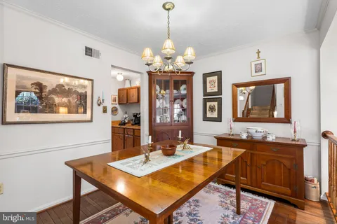 a dining room with wooden floor a chandelier a wooden table and chairs