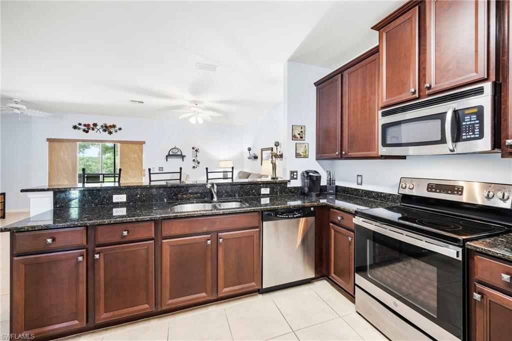 3916 Cherrybrook Loop Fort Myers, FL 33966 - Photo 4 of 31 Kitchen featuring dark wood cabinetry, a double basin sink, stainless steel appliances, and dark speckled countertops