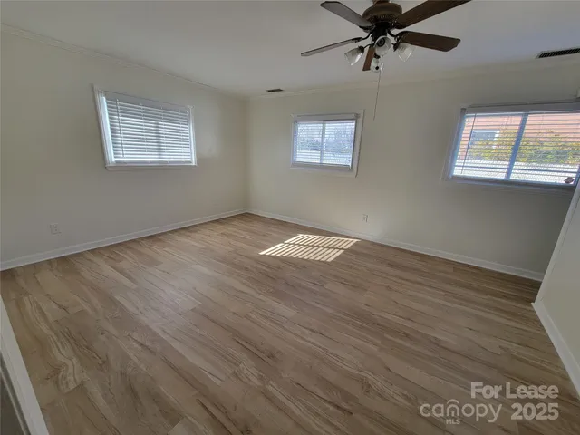 a view of an empty room with a window and wooden floor