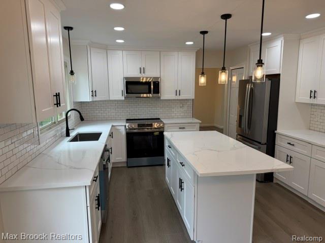 650 Deerfield Court Rochester, MI 48309 - Photo 7 of 28 Bright kitchen featuring white shaker cabinetry, stainless steel appliances, a center island with a quartz countertop, a subway tile backsplash, and wood-finish flooring