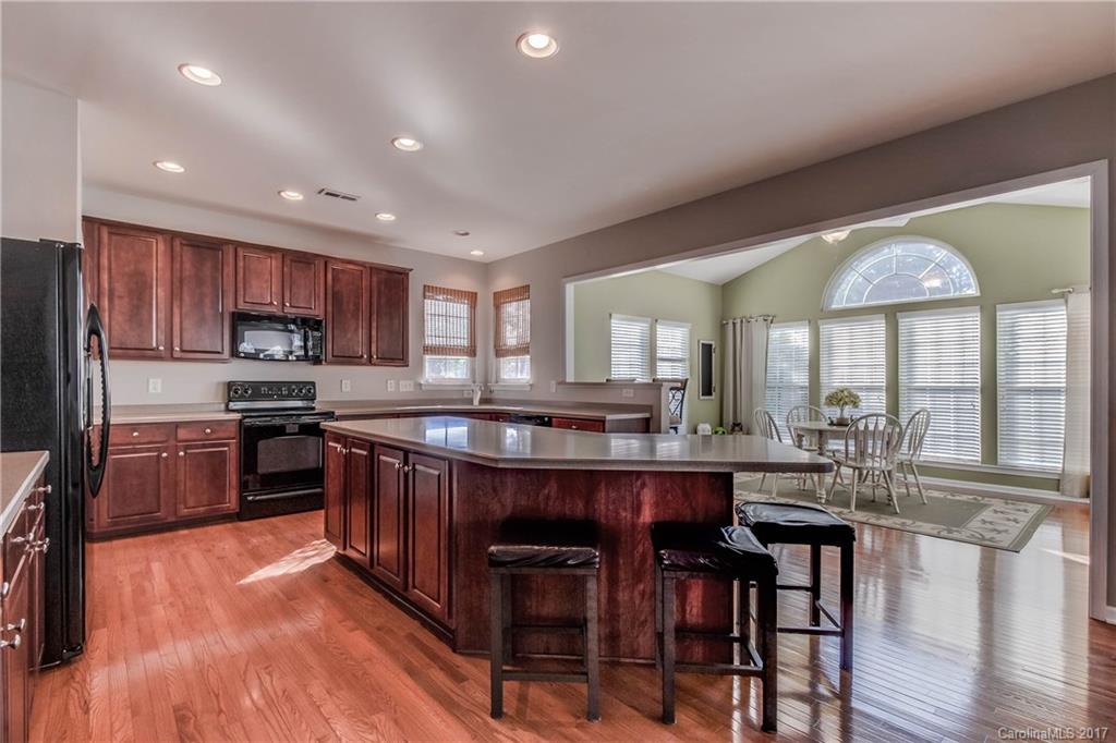 634 Panthers Way Fort Mill, SC 29708 - Photo 9 of 24 a kitchen with stainless steel appliances granite countertop a stove top oven a sink dishwasher a dining table and chairs with wooden floor