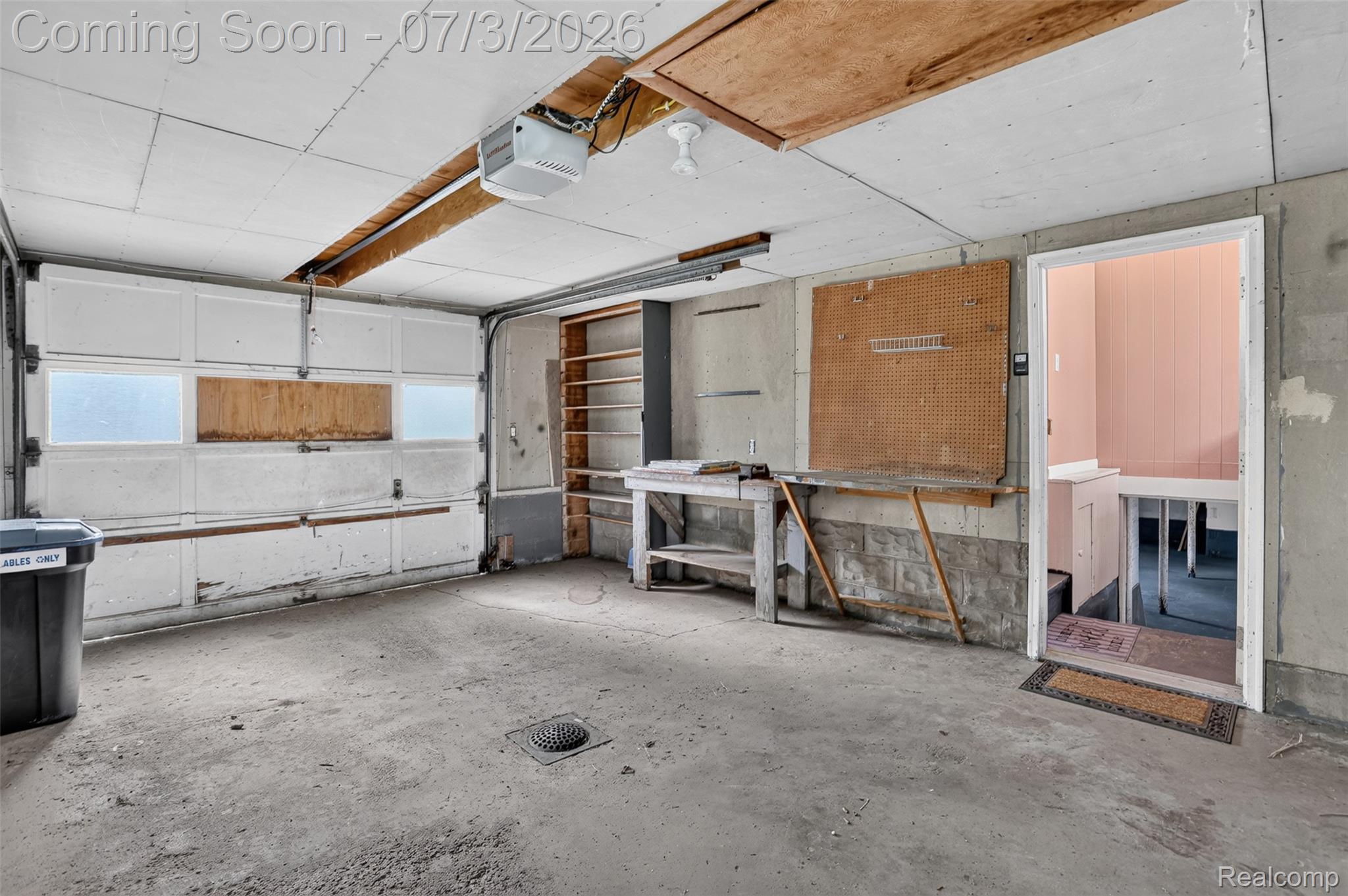 4322 Baker Road Bridgeport, MI 48722 - Photo 25 of 29 Attached garage featuring a concrete floor with a floor drain, overhead lighting, and a built-in workbench with shelving
