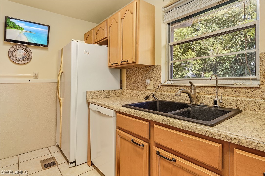 8185 Egret Road Fort Myers, FL 33967 - Photo 17 of 35 a kitchen with a sink a refrigerator and cabinets