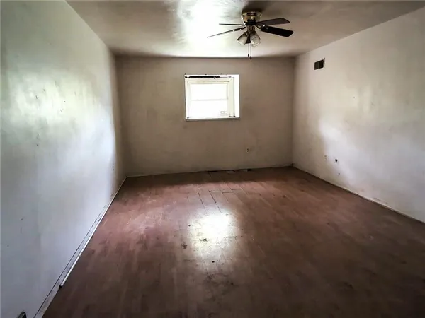en empty room with windows and ceiling fan