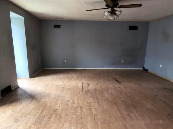 an empty room with wooden floor and windows