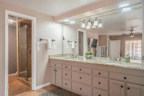 a bathroom with a granite countertop sink mirror and next to a window
