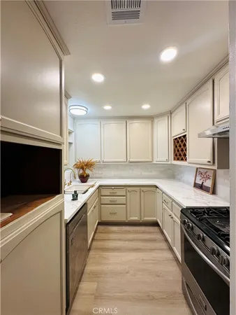a large white kitchen with stainless steel appliances granite countertop a stove and a sink