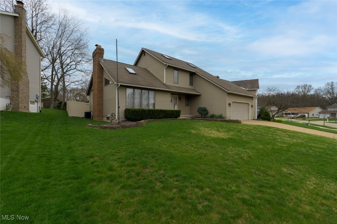819 Bridge Road Akron, OH 44312 - Photo 2 of 33 View of front of home featuring central AC, concrete driveway, an attached garage, and a large front yard