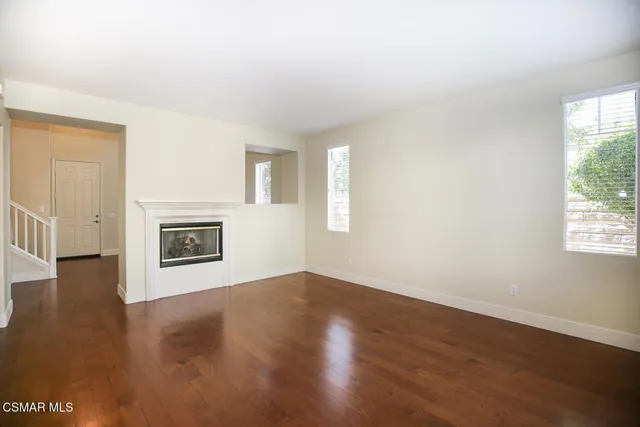 an empty room with windows and fireplace