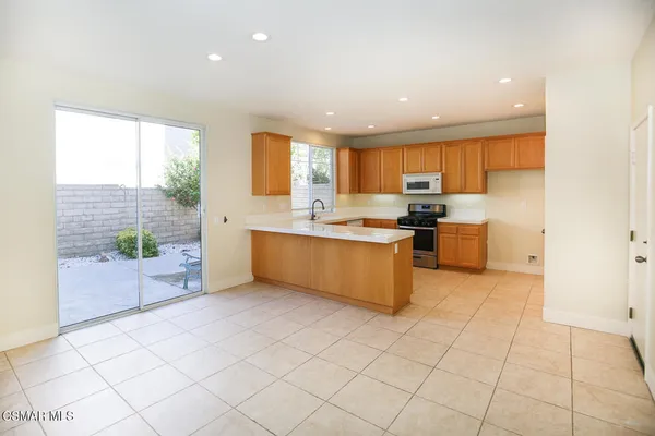 a large kitchen with stainless steel appliances a large counter top a stove a chimney a sink and a refrigerator