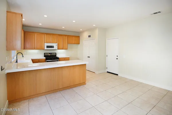 a kitchen with stainless steel appliances a sink a stove a microwave a sink a refrigerator and cabinets
