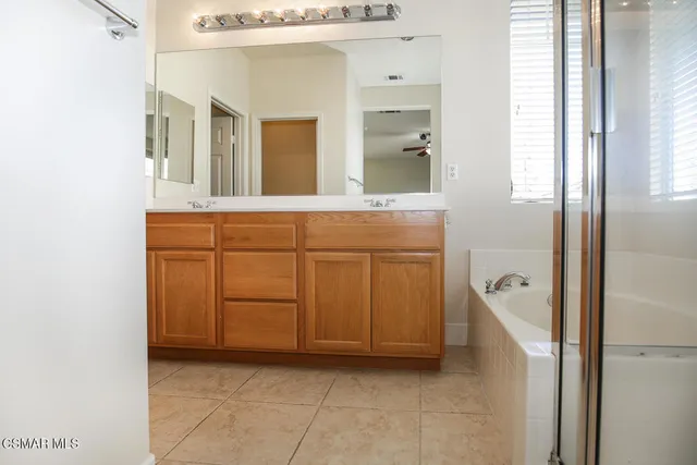 a bathroom with a double vanity sink a mirror and a bathtub
