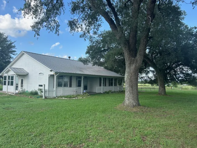 a front view of house with a garden and trees
