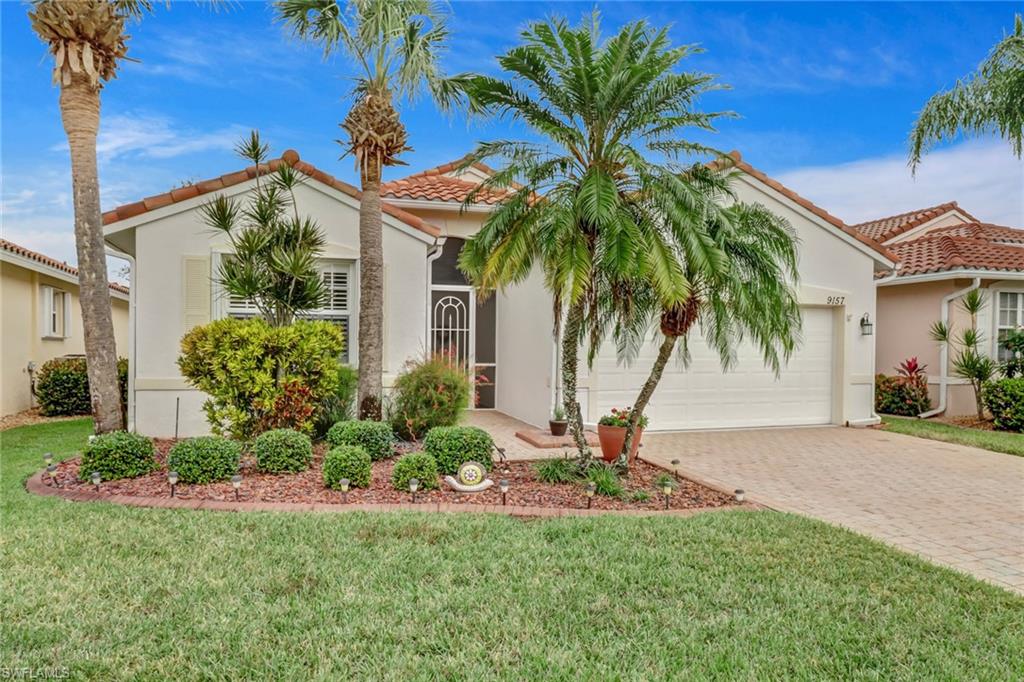 9157 Springview Loop Estero, FL 33928 - Photo 2 of 47 a front view of a house with a yard and potted plants