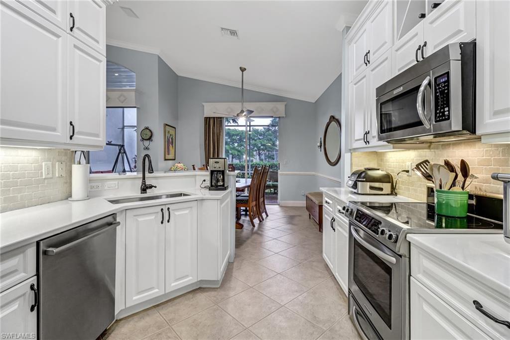 9157 Springview Loop Estero, FL 33928 - Photo 8 of 47 a kitchen with stainless steel appliances granite countertop a sink a stove and a microwave
