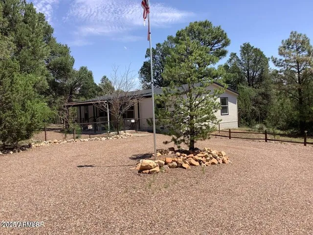 a backyard of a house with table and chairs under an umbrella