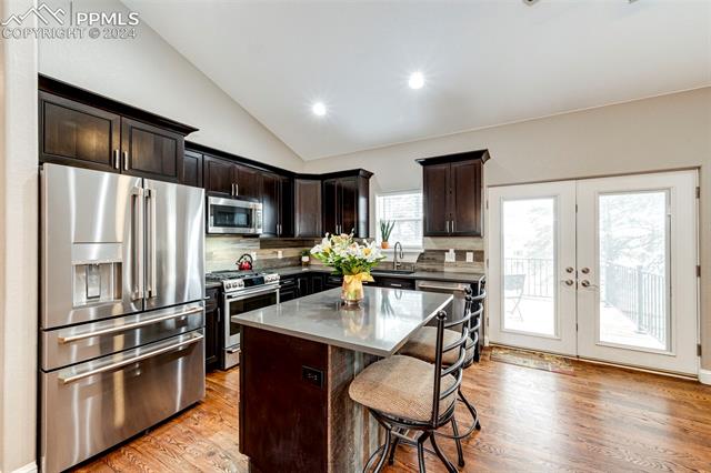 711 Pine Ridge Street Elizabeth, CO 80107 - Photo 14 of 39 Kitchen with backsplash, appliances with stainless steel finishes, dark brown cabinets, and vaulted ceiling