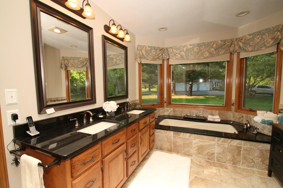 11627 Prestwick Road Belvidere, IL 61008 - Photo 16 of 25 a bathroom with a bathtub double vanity sink and a large mirror