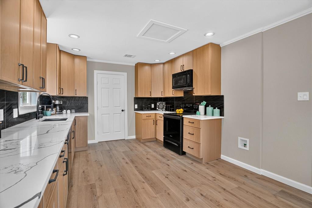 130 R And R Drive Springtown, TX 76082 - Photo 12 of 40 Kitchen featuring wood-finish flooring, light wood cabinetry, black hardware, black tile backsplash, and white countertops