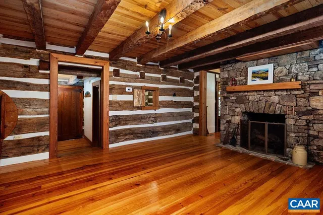 a view of an empty room with wooden floor a fireplace and a window