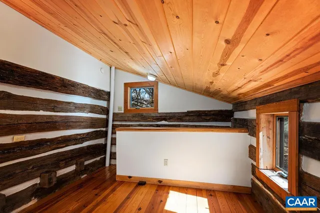 a view of an empty room with wooden floor fireplace and a window