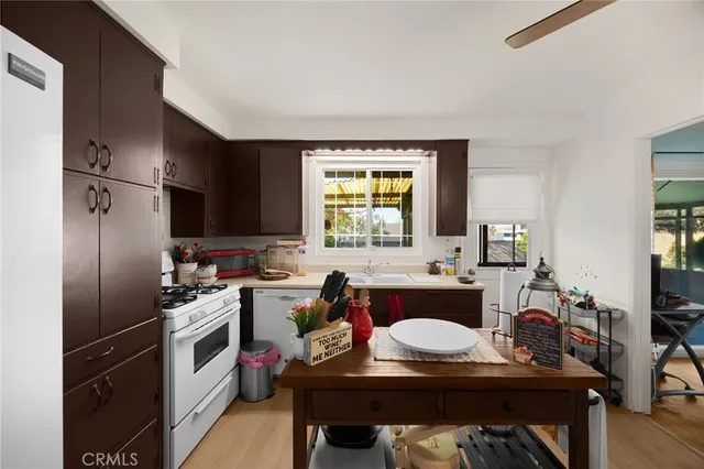 a kitchen with a refrigerator a sink dishwasher a stove and a dining table with wooden floor