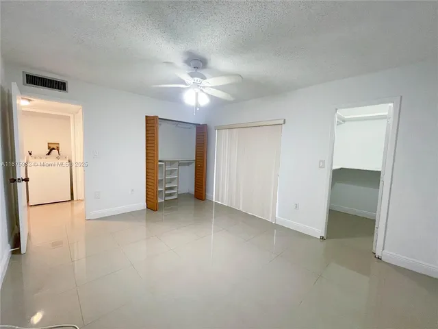 an empty room with closet and a chandelier fan