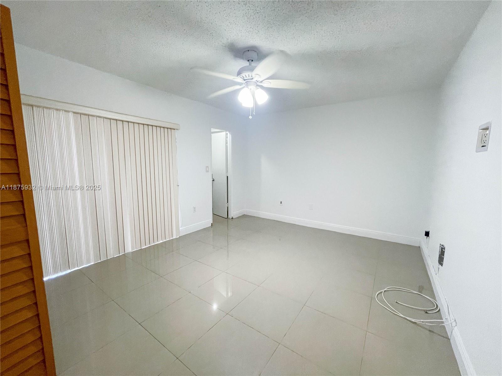 10370 Southwest 220th Street, Unit 129 Miami, FL 33190 - Photo 3 of 8 an empty room with a ceiling fan and a window