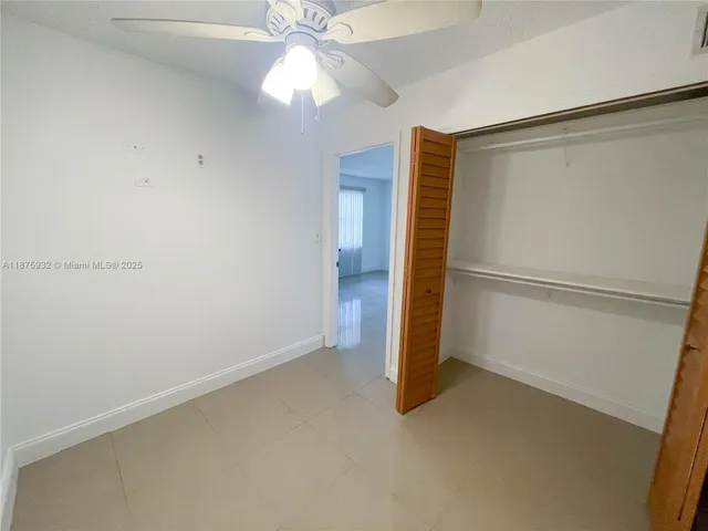 an empty room with a walk in closet and a ceiling fan