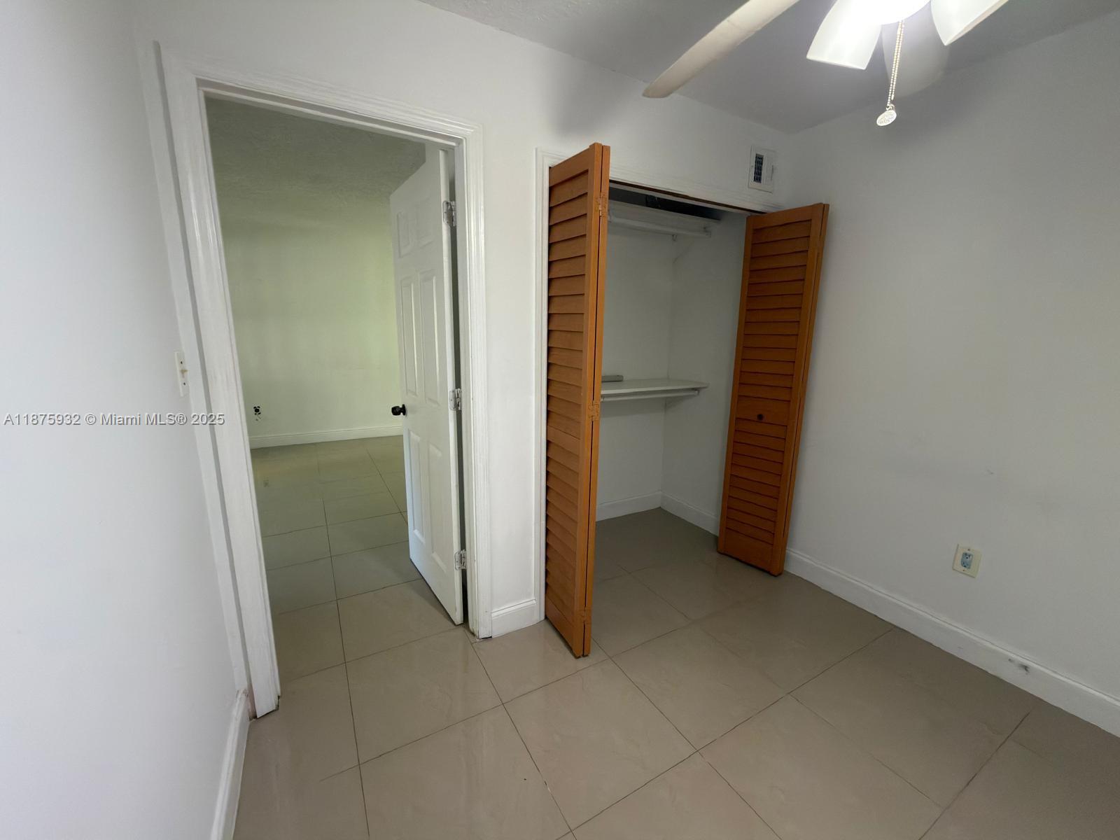 10370 Southwest 220th Street, Unit 129 Miami, FL 33190 - Photo 6 of 8 an empty room with closet and a chandelier fan