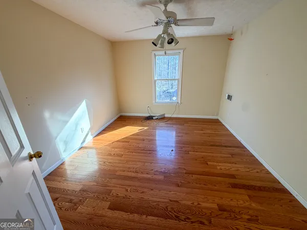 a view of an empty room with wooden floor and a window