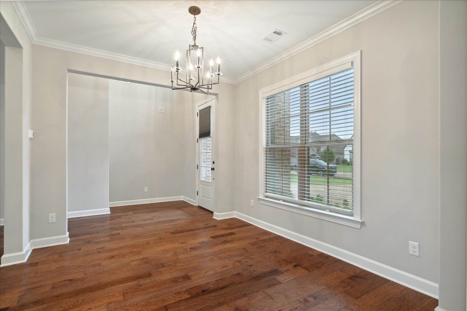 6437 Rutherford Circle Arlington, TN 38002 - Photo 15 of 40 Empty room with an inviting chandelier, dark hardwood / wood-style flooring, and crown molding