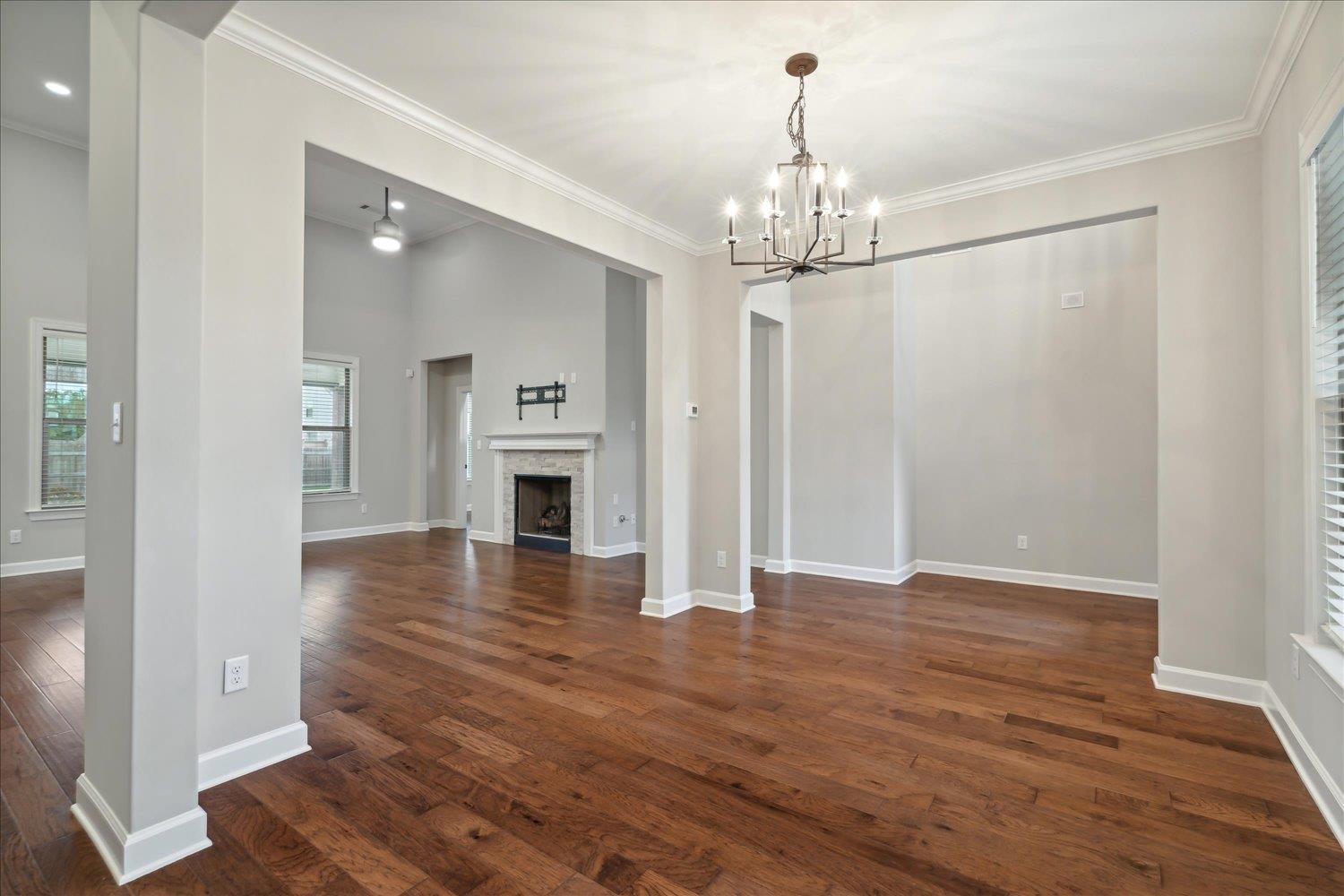6437 Rutherford Circle Arlington, TN 38002 - Photo 16 of 40 Unfurnished living room featuring ornamental molding, dark hardwood / wood-style flooring, and a notable chandelier