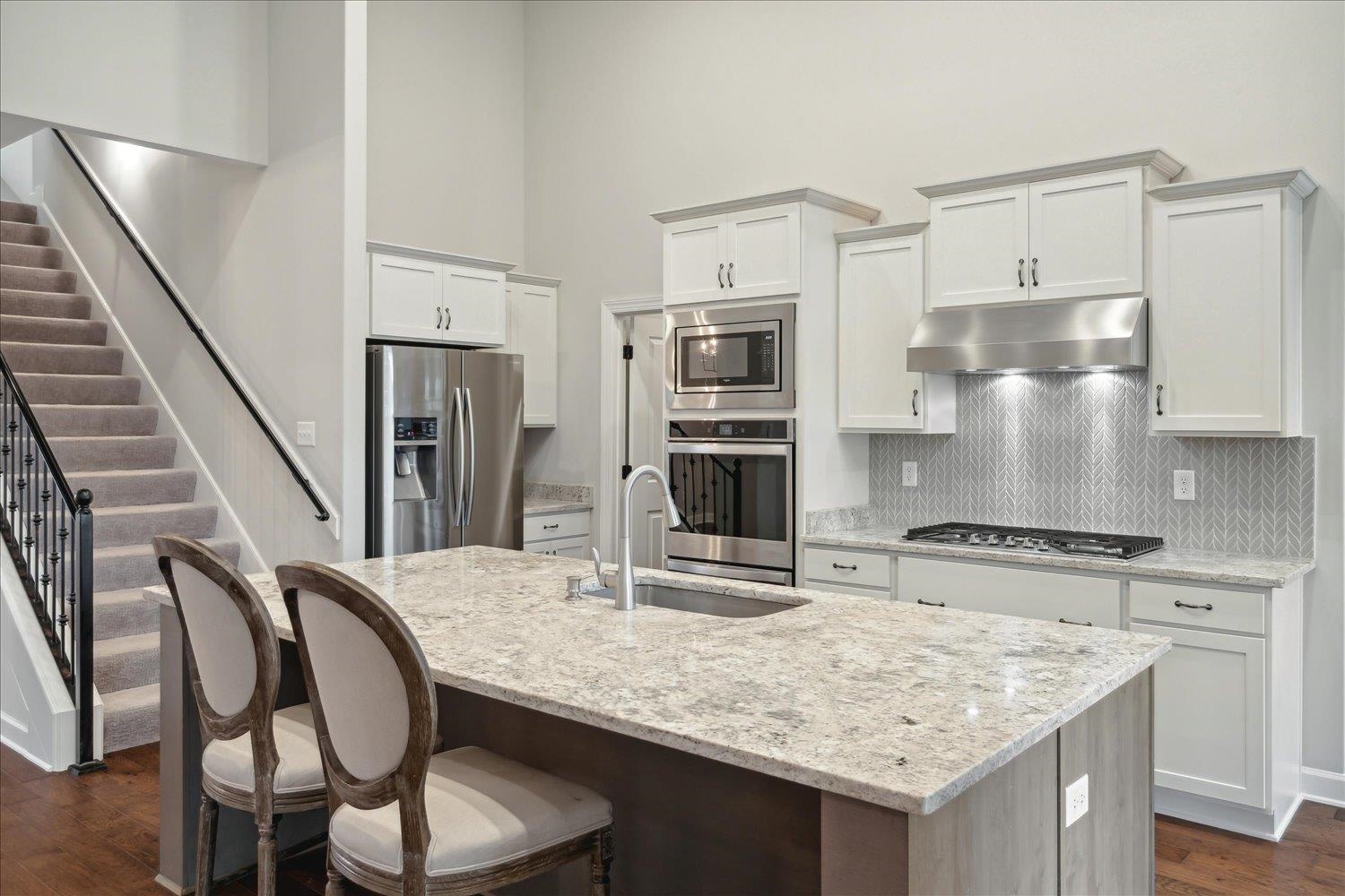 6437 Rutherford Circle Arlington, TN 38002 - Photo 4 of 40 Kitchen with a kitchen island with sink, light stone counters, sink, dark hardwood / wood-style floors, and appliances with stainless steel finishes