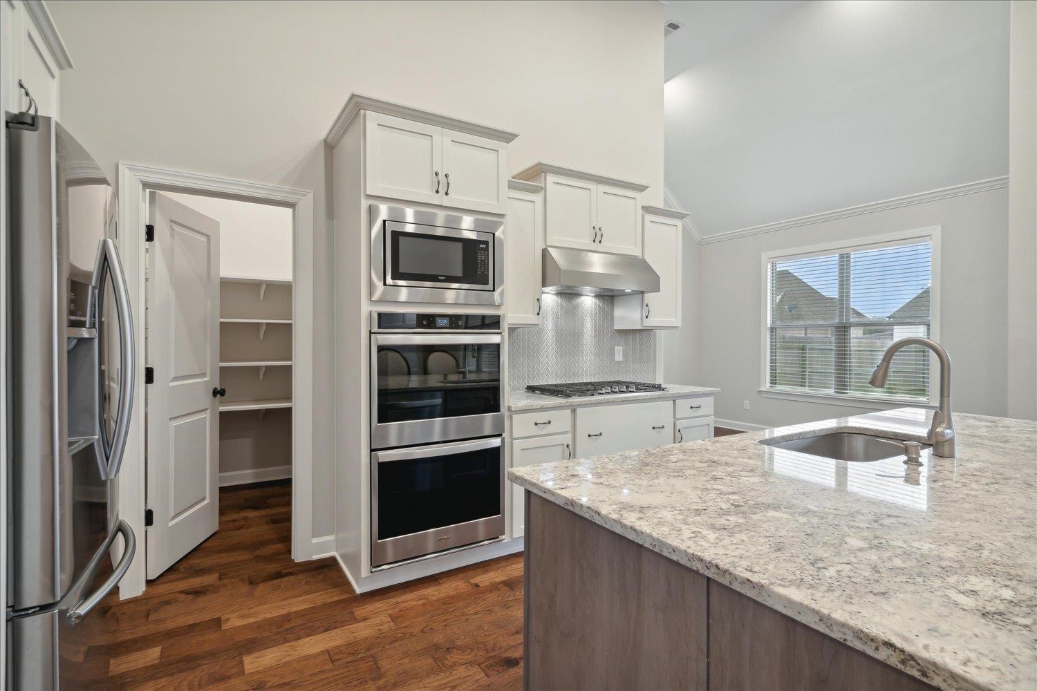 6437 Rutherford Circle Arlington, TN 38002 - Photo 5 of 40 Kitchen with crown molding, appliances with stainless steel finishes, light stone counters, sink, and dark hardwood / wood-style floors