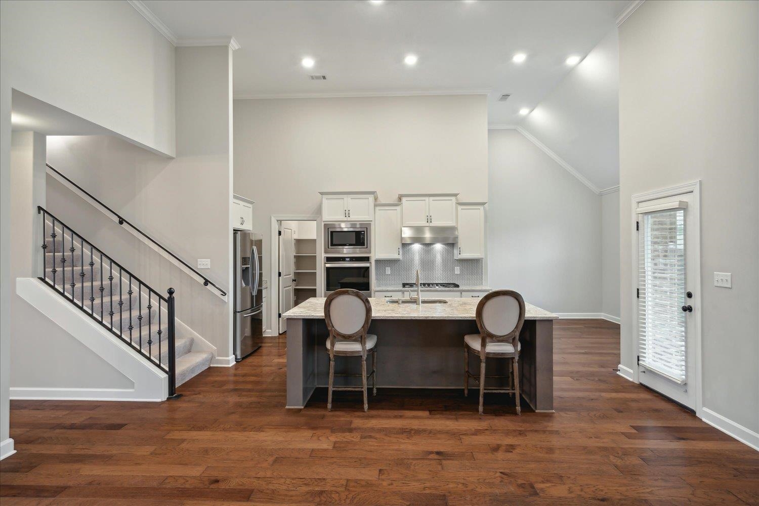 6437 Rutherford Circle Arlington, TN 38002 - Photo 6 of 40 Kitchen featuring white cabinetry, stainless steel appliances, an island with sink, light stone countertops, and dark hardwood / wood-style floors