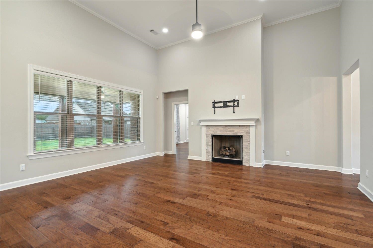 6437 Rutherford Circle Arlington, TN 38002 - Photo 10 of 40 Unfurnished living room with dark wood-type flooring, ornamental molding, a stone fireplace, and a towering ceiling