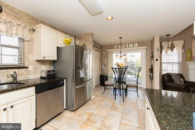 a kitchen with granite countertop a refrigerator a stove a sink and dining table with wooden floor