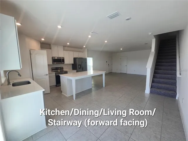 a view of a kitchen with fridge and wooden floor