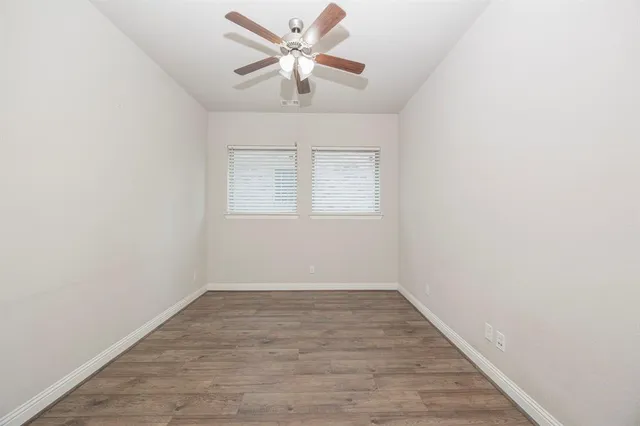 an empty room with wooden floor and a ceiling fan