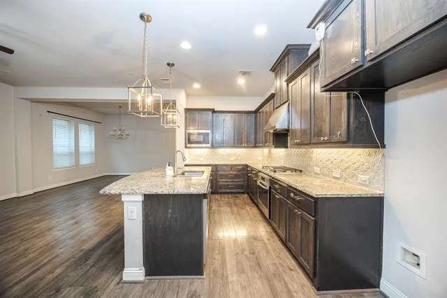 a kitchen with stainless steel appliances granite countertop wooden floors sink and stove