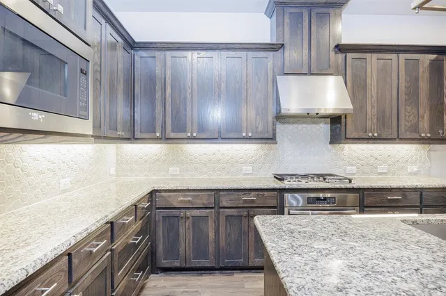 a kitchen with granite countertop wooden cabinets and stainless steel appliances