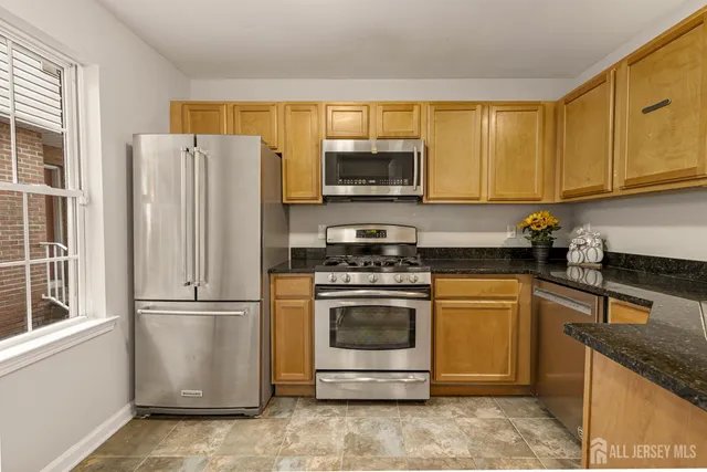 a kitchen with stainless steel appliances granite countertop a refrigerator stove a sink and a microwave