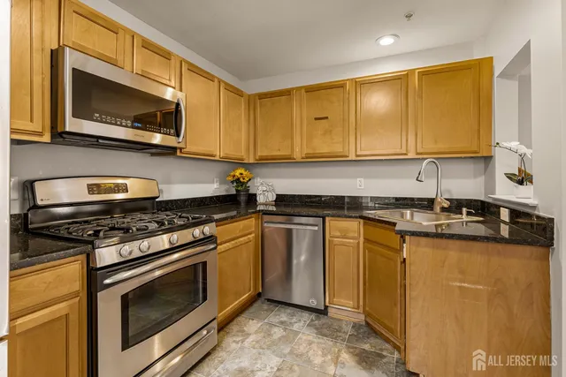 a kitchen with stainless steel appliances granite countertop a stove a sink and a microwave