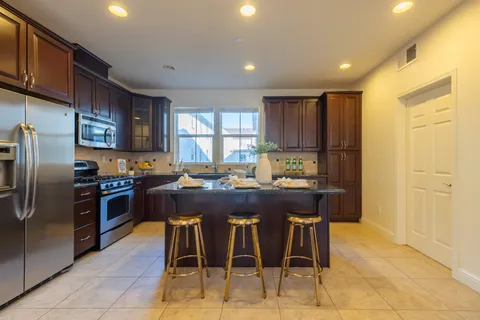 a kitchen with stainless steel appliances granite countertop a refrigerator a sink a stove a microwave and chairs