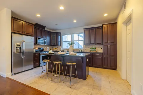 a kitchen with stainless steel appliances granite countertop a sink counter space cabinets a stove and a large window