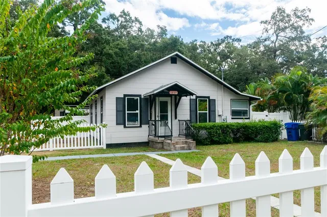 a view of house that has a lot of white walls plants and large trees