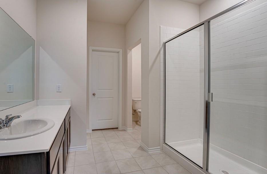 1614 Potomac Lane Blue Ridge, TX 75424 - Photo 8 of 18 Bathroom featuring a glass-enclosed shower, white subway tile shower surround, dark wood vanity with white countertop, integrated sink, and chrome faucet